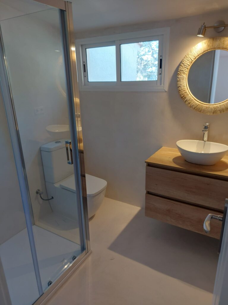 Baño reformado con plato de ducha y mueble suspendido por JGM Reformas