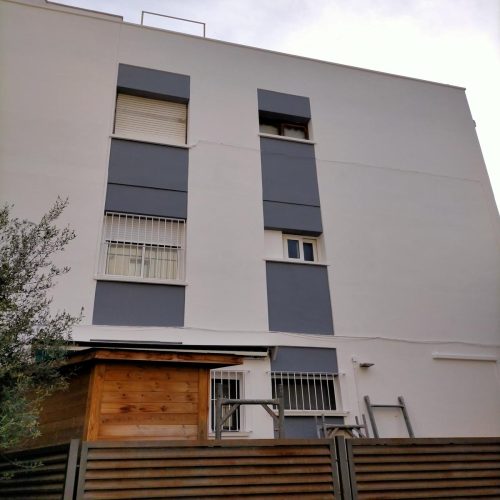 Fachada de bloque de pisos rehabilitada con porche de madera