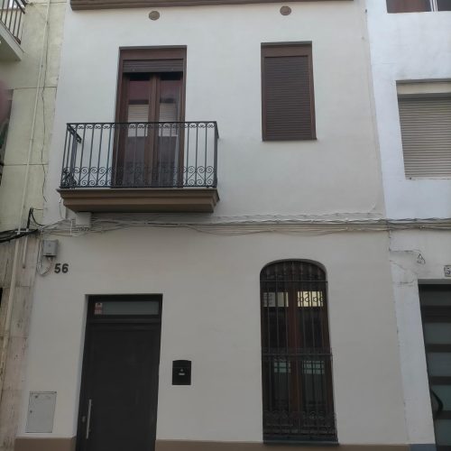 Fachada de casa entre medianeras reformada, con acceso y balcón