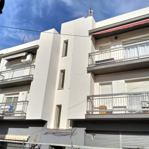 Bloque de viviendas con fachada blanca y balcones tras la reforma