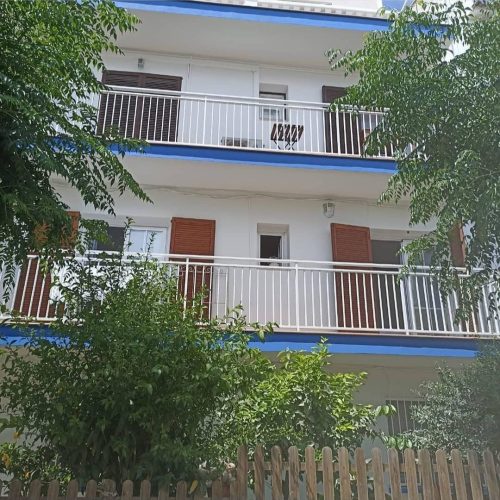 Fachada de edificio con balcones y toldos azules rehabilitada