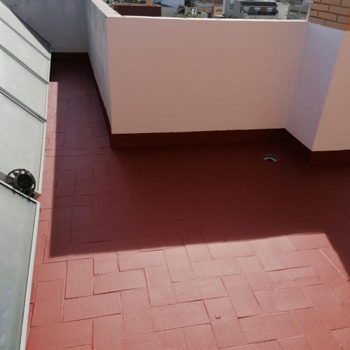 Terraza con pavimento rojo y muretes pintados tras impermeabilizar